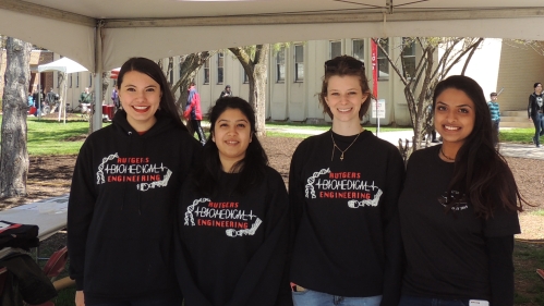 four young women standing side-by-side outdoors wearing a black Rutgers Biomedical Engineering sweatshirts