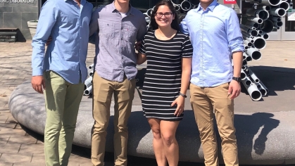 Four smiling students standing in front of Running Man sculpture