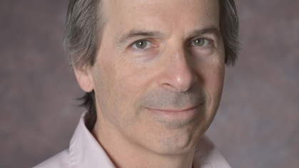 head shot of man with light brown hair wearing a light pink button down shirt