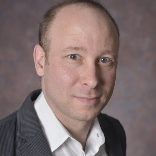 head shot of man wearing a grey suit jacket and white button down shirt