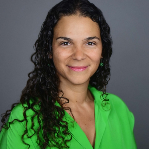 head shot of woman with long curly black hair wearing a bright green blouse