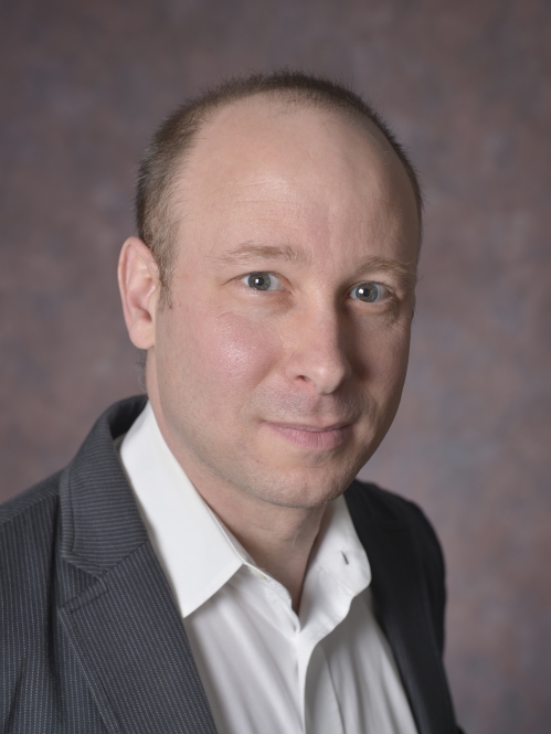 head shot of man wearing a grey suit jacket and white button down shirt