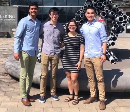 Four smiling students standing in front of Running Man sculpture