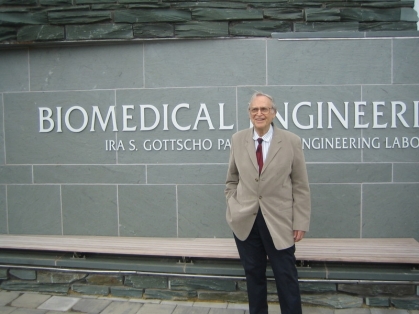 elderly man in a suit and tie standing in front of the biomedical engineering building 