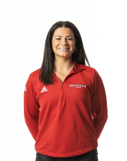 Female college student poses from the waist up with her hands behind her back. She has long black hair and is wearing red Rutgers pulloever.
