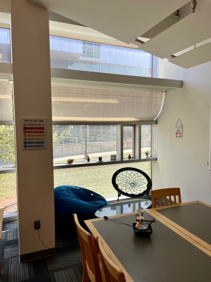 A corner of the wellness room is shown, with a table, beanbag chair, and bungee chair. A small desk fountain sits on the table.