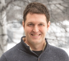 Headshot of malle with short brown hair wearing a grey pullover.