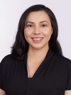 Headshot of woman with long black hair wearing a black blouse.