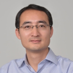 Headshot of male with eyeglasses wearing a light blue collared shirt.